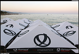 Alušta (Алушта) - pohled na moře přes slunečníky s reklamou na ukrajinskou vodku Chortycja (Хортиця)