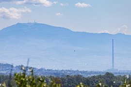 Komín v Baia Mare – nejvyšší stavba v celém Rumunsku. V pozadí mohutná hora Mogoșa (Fekete hegy) v Gutinských horách (2025)