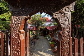 Vyřezávaná sikulská brána u vstupu do restaurace Cetate, nechybí elektrický ohradník (2024)