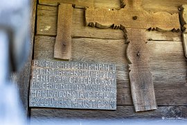 Deska píše o "dřevěném kostelu zasvěceném svatým archandělům" (2025)