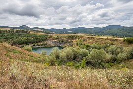 Pohled na severní okraj Munții Perșani od lomu v Racoși. Uprostřed výrazný vrch Tipia Ormenișului (750 m), vpravo od něj Muntele Negru – Fekete-Hegy (967 m), zcela vpravo zarovnané vrcholky Motilor a Tolvajos. Výrazný vrchol vlevo Tipia Racoșului (820 m) už patří do Harghity. (2024)